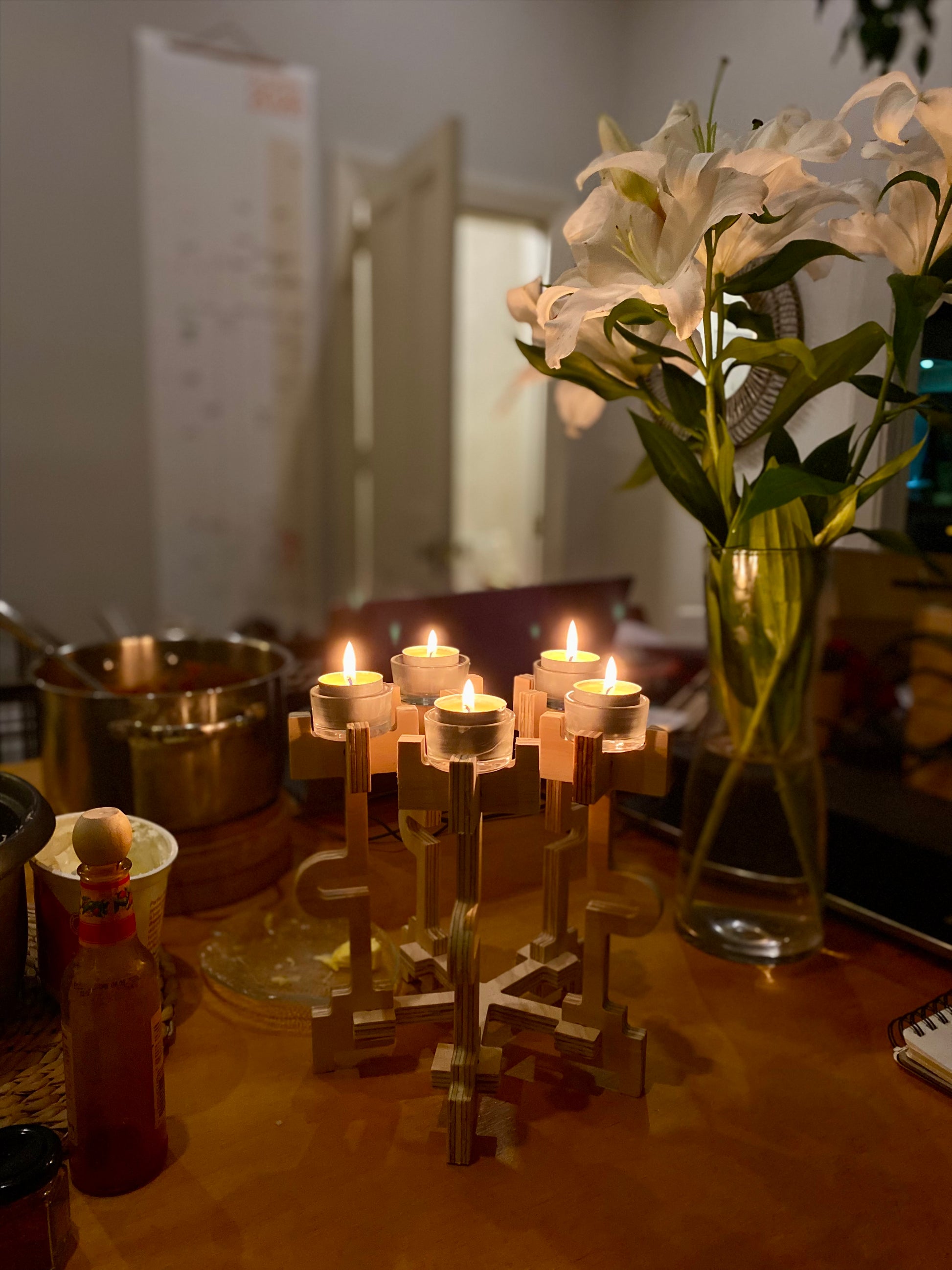 Candle holder with lit candles on a table next to a vase of flowers.